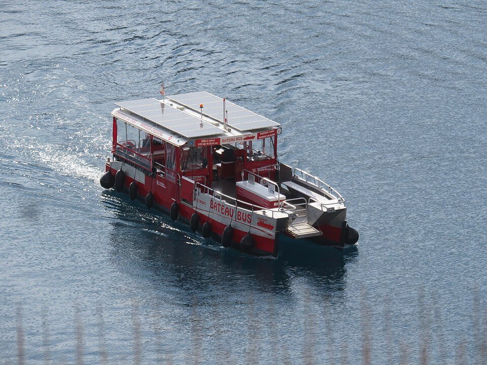 A small ferry crossing the harbor below the rock